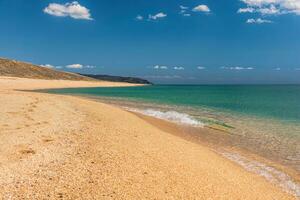 vuoto bellissimo morbido d'oro sabbioso spiaggia e mare. isolato spiaggia, no le persone. asciutto soleggiato giorno Immagine, dove oro sabbia incontra mare e Smeraldo mare incontra blu nuvoloso cielo. copia spazio, pieno telaio. foto