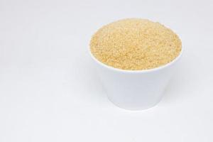 zucchero di canna in una tazza bianca su sfondo bianco foto