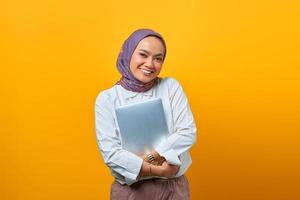 il ritratto della donna asiatica sorridente porta il computer portatile? foto