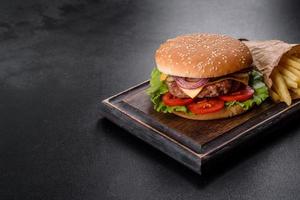 hamburger di manzo artigianale e patatine fritte su sfondo nero foto