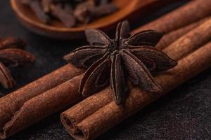 anice, stecche di cannella e chiodi di garofano in un cucchiaio di legno, macro foto