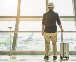 un viaggiatore maschio che indossa un cappello grigio che si prepara a viaggiare foto