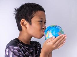 un ragazzo porge il globo e lo bacia sul globo. foto