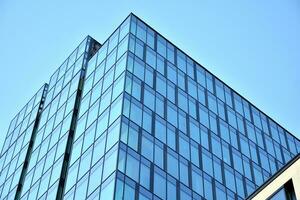 bicchiere edificio con trasparente facciata di il edificio e blu cielo. strutturale bicchiere parete riflettendo blu cielo. astratto moderno architettura frammento. contemporaneo architettonico sfondo. foto