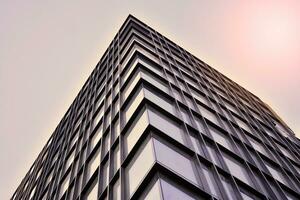 moderno ufficio edificio con bicchiere facciata su un' chiaro cielo sfondo. trasparente bicchiere parete di ufficio costruzione. foto