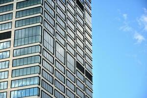 moderno ufficio edificio con bicchiere facciata su un' chiaro cielo sfondo. trasparente bicchiere parete di ufficio costruzione. foto