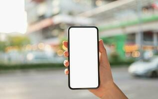 mano Tenere nero smartphone con vuoto schermo per grafico Schermo montaggio a shopping centro commerciale sfondo. foto