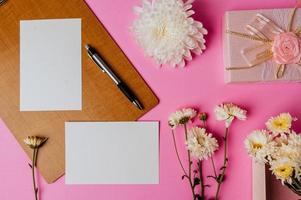 confezione regalo rosa, fiore, penna, tavola di legno e biglietto bianco su rosa foto