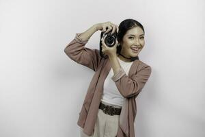 allegro giovane asiatico donna turista in piedi con telecamera assunzione foto isolato su bianca studio sfondo