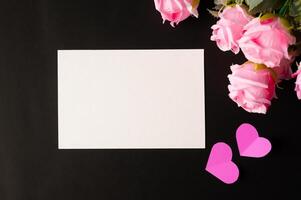 carta bianca e fiori rosa incollati su uno sfondo nero foto