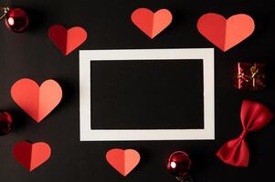 cornice per foto bianca e carta cuore rosso incollata su sfondo nero.