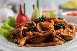 calamari saltati in padella con pasta di curry in piatto bianco. foto
