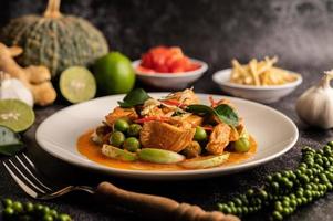 curry verde secco con pollo in piatti bianchi su cemento nero foto