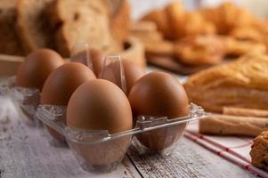 uova in pannelli di plastica e pane che viene posto su un legno bianco