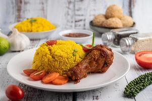 biryani di pollo in un piatto con spezie su un pavimento di legno bianco foto