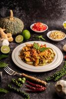 curry verde secco con pollo in piatti bianchi su cemento nero foto