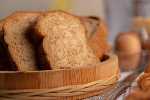 fette di pane poste in un piatto di legno su un tavolo di legno bianco. foto