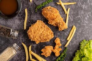 pollo fritto e patatine fritte sul pavimento di cemento nero. foto