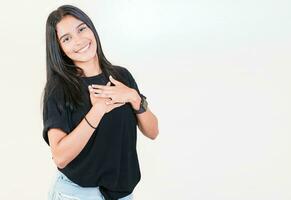 grato adolescenziale ragazza sorridente con mani su il petto isolato. positivo latino ragazza con mani su il petto. grato persone con mani su cuore foto