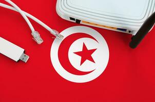 tunisia bandiera raffigurato su tavolo con Internet rj45 cavo, senza fili USB Wi-Fi adattatore e router. Internet connessione concetto foto