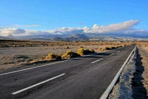 un vuoto strada nel il mezzo di un' deserto con un' montagna nel il sfondo foto