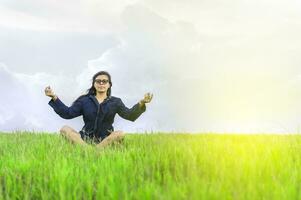 donna nel il campo seduta meditando, donna fare yoga nel il freddo campo foto