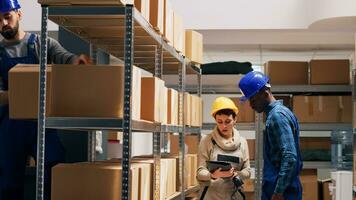 diverso deposito lavoratori utilizzando digitale tavoletta per scansione merce, puntamento scanner a codici a barre su scatole per dai un'occhiata azione la logistica. giovane dipendenti nel tuta da lavoro Lavorando con carico inventario. foto