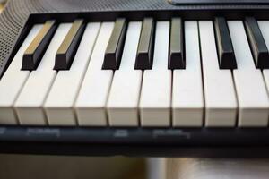 avvicinamento di pianoforte chiavi. pianoforte nero e bianca chiavi e pianoforte tastiera musicale strumento posto a il casa balcone durante soleggiato giorno. foto