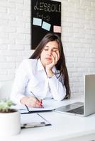 donna bruna triste o depressa che dorme al suo posto di lavoro