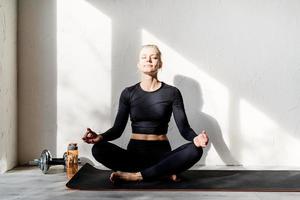 giovane donna bionda che fa yoga o medita a casa