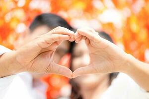 avvicinamento di coppia mani fabbricazione cuore forma, mano fabbricazione cuore cartello, persona Tenere mani foto