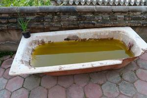 vasca da bagno rotta nel deserto con acqua sporca all'interno foto