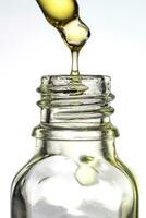 pipetta con giallo far cadere scrosciante in il bottiglia su bianca isolato sfondo. facciale olio vitamina campione foto