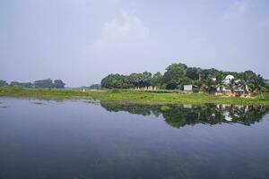 riflessione di alberi nel il lago acqua contro il blu cielo paesaggio campagna nel bangladesh foto