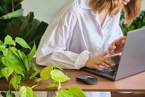 Da donna mani a un' il computer portatile contro un' sfondo di verde. foto