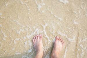 primo piano di una donna donna e uomo coppia amante piedi nudi camminare e impronta a bagnato sulla spiaggia romantica luna di miele. vacanza sulla spiaggia dell'oceano, piedi sulla sabbia del mare. l'ombra del sole colpisce la sabbia. viaggiare foto