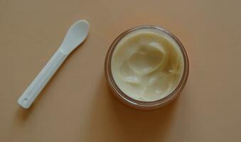 plastica vaso di bellezza crema o maschera per viso cura con spatola su pastello sfondo, superiore Visualizza. concetto di cura della pelle cosmetici, cosmetico terme medico pelle cura. naturale cosmetici concetto. foto