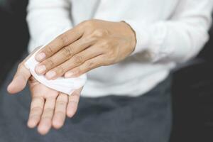 donna utilizzando fazzoletto di carta carta pulito il tuo mani per rimuovere germi. foto