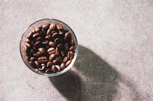 chicchi di caffè freschi in una ciotola di vetro su uno sfondo foto