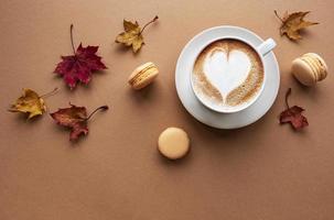 tazza di caffè e foglie secche su sfondo marrone