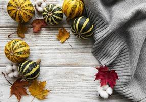 foglie di acero di autunno, zucche e sciarpa di lana su un fondo di legno. foto