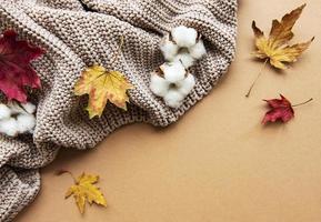 maglione di lana lavorato a maglia o plaid, foglie secche su sfondo marrone