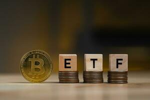 bitcoin oro moneta parole etf di legno blocchi su righe pila monete e sfocato grafico sfondo, criptovaluta bitcoin dimezzare concetto. il bitcoin etf quale si riferisce per scambio scambiato finanziare. foto