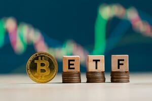 bitcoin oro moneta parole etf di legno blocchi su righe pila monete e sfocato grafico sfondo, criptovaluta bitcoin dimezzare concetto. il bitcoin etf quale si riferisce per scambio scambiato finanziare. foto