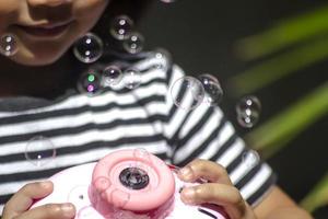 giocattolo creatore di bolle sulla mano di una bambina foto