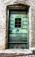 Porta in legno verde con finestra danneggiata dalle intemperie a san martino di castrozza, trento, italia foto