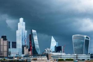 City of London business district grattacieli lucenti contro il cielo tempestoso.