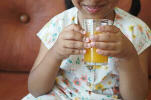 bambino mano Tenere un' bicchiere di arancia succo foto