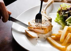 bistecca di braciola di maiale con insalata e patatine fritte foto