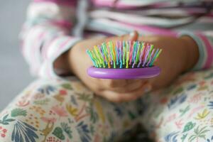 bambino mano Tenere un' colorato capelli spazzola a casa , foto